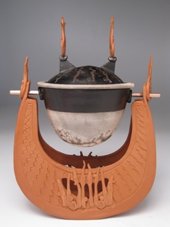 Carol Smeraldo . 2009. Learned Boat: Percolating Impressions. Wheel thrown, hand built, sculpted, carved, inlayed, twice burnished terra sigillatta. Lantz clay, black and white naked raku slip resist lidded container, with a large marble inside, suspended on a copper rod. 30.5 h x 20.5 l x 15 w cm.