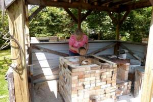  Judy Blake loading sawdust around a saggared pot for firing.