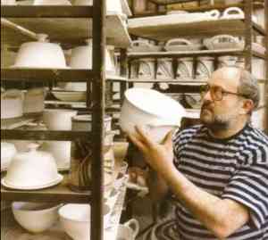 Robin Hopper in his studio with shelves of his functional ware